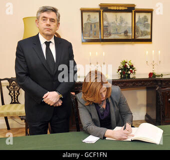 Premierminister Gordon Brown steht vor der Bühne, als seine Frau Sarah ihren Namen in das Kondolenzbuch einträgt. Das wurde gestern in der polnischen Botschaft im Portland Place, London, eröffnet, nachdem Polens Präsident Lech Kaczynski zu den 96 Personen gehörte, die am Samstag bei einem Absturz eines Flugzeugs nach Russland ums Leben kamen. Stockfoto