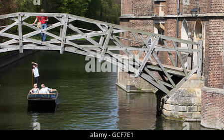 Ein Punt macht seinen Weg unter der Mathematical Bridge am Queens' College am Fluss Cam im Zentrum von Cambridge, während sich die Menschen quer durch Großbritannien in der Frühlingssonne sonnen. Stockfoto