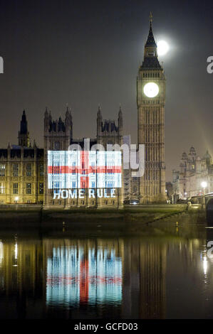 Ein Bild der englischen Flagge mit der Aufschrift „Home Rule“ wurde von der Demokratiegruppe POWER2010 im Rahmen eines St George's Day-Protestes auf die Houses of Parliament projiziert, um ein Ende der Abstimmung von nicht-englischen Abgeordneten über englische Gesetze in Westminster zu fordern. Stockfoto