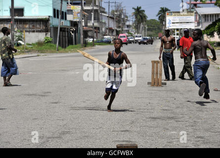 Ein junger Junge Fledermäuse in einer Straße Cricket-Spiel in Georgetown, Guyana. Stockfoto