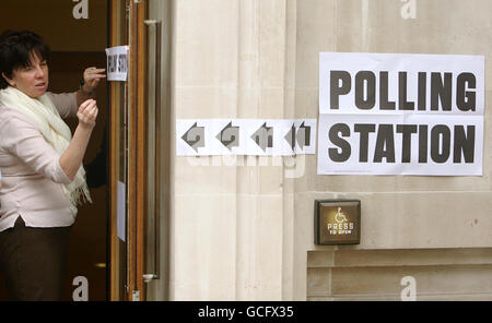 Ein Mitarbeiter positioniert ein Schild an der Tür eines Wahllokalen in der Methodist Central Hall in Westminster, im Zentrum von London, als bei den Parlamentswahlen in ganz Großbritannien Wahlen anstanden. Stockfoto