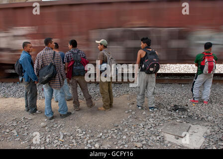 Zentralamerikanische Migranten warten als eine Beschleunigung Güterzug, den Sie hofften, an Bord geht sie durch hüpfen nördlich von Mexiko-Stadt. Stockfoto