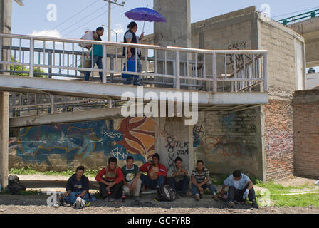 Zentralamerikanische Migranten warten unten einen Fußgängerweg für einen vorbeifahrenden northbound Zug zu hüpfen, auf ihrer Reise in die USA. Stockfoto