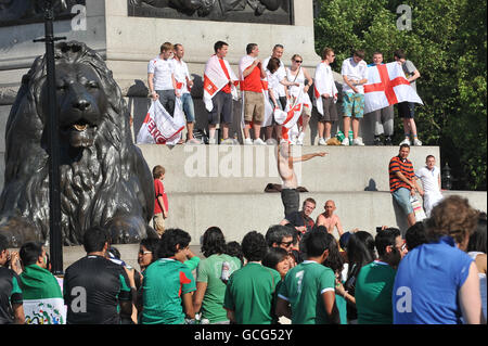 England-Anhänger auf der Basis von Nelsons Kolonne am Trafalgar Square genießen die warme Sonne vor dem Internationalen Freundschaftsspiel gegen Mexiko an diesem Abend. Stockfoto