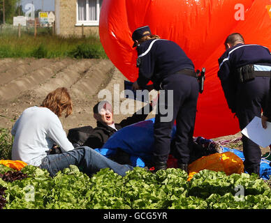 Jonathan Trappe wird von französischen Polizeibeamten verhört, nachdem er seine mit Helium gefüllten Ballons auf Ackerland in Moeres, Frankreich, landete. Der wagemutige Abenteurer hob vom Kent Gliding Club in Challock, nahe Ashford, ab und überquerte den Ärmelkanal, der in einem Stuhl unter mehreren Dutzend mit Helium gefüllter Ballons festgeschnallt war. DRÜCKEN SIE VERBANDSFOTO. Bilddatum: Freitag, 28. Mai 2010. Siehe PA Story ADVENTURE Balloons. Das Foto sollte lauten: Gareth Fuller/PA Wire Stockfoto