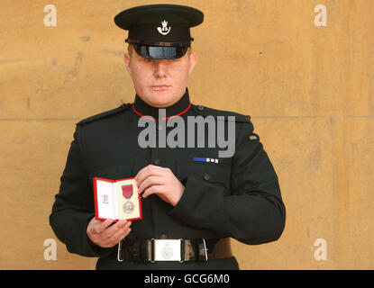 Rifleman Paul Jacobs besitzt die George-Medaille, die ihm für seine Tapferkeit in Afghanistan verliehen wurde, die ihm von der britischen Königin Elizabeth II. Bei einer Investiturzeremonie im Buckingham Palace, London, verliehen wurde. Stockfoto