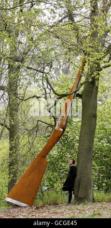 Die Künstlerin Cornelia Parker mit ihrer Arbeit "Landscape with Gun and Tree" eine 9 m hohe Stahlflinte, die an einer Buche angelehnt ist, eine der neuen Arbeiten, die heute offiziell auf Jupiter Artland in der Nähe von Edinburgh vorgestellt werden. Stockfoto