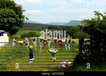 An einem Tor zum Feld, wo der Farmer Garry Purdham, 31, während des Schießschlages in Cumbria von Derrick Bird erschossen wurde, werden Blumen-Tribute hinterlassen. Stockfoto