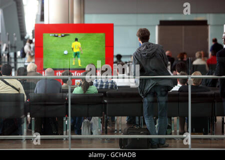 Passagiere, die am Flughafen Heathrow in Terminal 5 abfliegen, sehen sich das Eröffnungsspiel der Fußball-Weltmeisterschaft 2010 an. Stockfoto