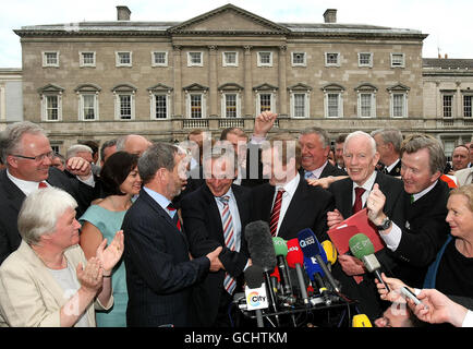 Enda Kenny (Mitte, rot gestreifte Krawatte), Anführerin von Fine Gael, lächelt, als er Richard Brutons (Mitte links) Hand auf dem Sockel des Leinster House schüttelt, nachdem er die Abstimmung auf einer entscheidenden parlamentarischen Parteisitzung für die Führung der Partei gewonnen hatte. Stockfoto