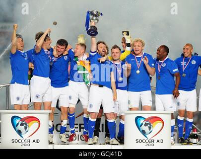 Der Rest der Welt Kapitän Michael Sheen (Mitte) hebt die an Trophäe, nachdem sein Team 2010 das Spiel Socceraid gewonnen hatte Old Trafford Stockfoto