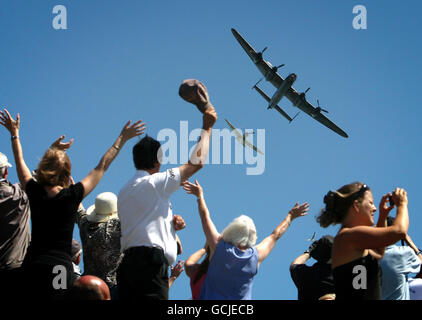 Die Zuschauer winken, während ein Lancaster Bomber und ein Spitfire das National Memorial in Capel-le-Ferne, Kent, im Rahmen einer Veranstaltung anlässlich des 70. Jahrestages der Schlacht von Großbritannien überwölben. Stockfoto