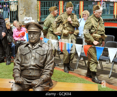 Eine Gruppe von Männern, die als Home Guard des Britanniens der 40er Jahre gekleidet waren, gehen an einer Bronzestatue des Hauptmanns Mainwaring vorbei, gespielt von dem Schauspieler Arthur Lowe, nachdem sie heute Nachmittag im Stadtzentrum von Thetford, Norfolk, enthüllt wurde. Stockfoto