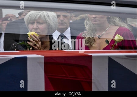 Heidi Kirkpatrick (im rosa Kleid), die Frau von Corporal Jamie Kirkpatrick, 32, von 101 Engineer Regiment, schaut mit anderen Trauernden, wie der Sarg ihres Mannes entlang der High Street in Wootton Bassett, Wiltshire, gefahren wird. Stockfoto