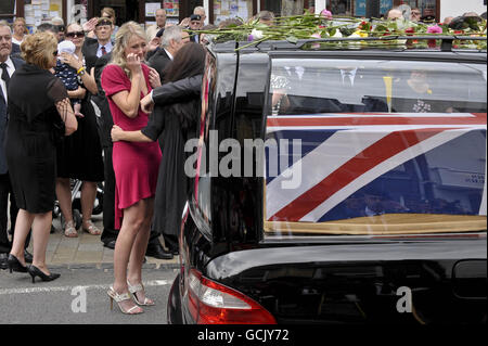 Heidi Kirkpatrick (im rosa Kleid), die Frau von Corporal Jamie Kirkpatrick, 32, vom 101 Engineer Regiment, beobachtet, wie der Sarg ihres Mannes entlang der High Street in Wootton Bassett, Wiltshire, gefahren wird. Stockfoto