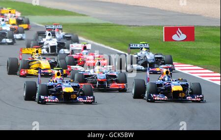 Mark Webber von Red Bull Racing (links) führt vom Teamkollegen Sebastian Vettel beim British Grand Prix von Santander auf dem Silverstone Circuit in Northampton in die erste Kurve. Stockfoto