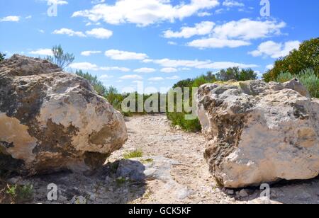 Weg durch zwei Kalkfelsen unter blauem Himmel mit Wolken mit native Grünpflanzen in Western Australia. Stockfoto