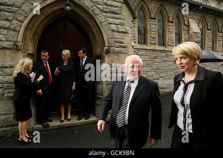 Verkehrsminister Noel Dempsey (zweite links), Ministerin für Soziales und Familie Mary Hanafin (dritte links) und Finanzminister Brian Lenihan (vierte links) Schutz in einem Dorrway vor dem Regen als Tainaiste Mary Coughlan (rechts) am Entfernungsdienst für ehemalige Generalstaatsanwalt Rory Brady in der Church of the Sacred Heart, Donnybrook, Dublin vorbeigeht. Stockfoto