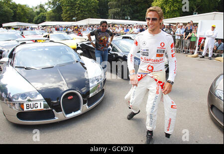 Formel-1-Weltmeister Jenson Button geht beim Festival of Speed in Goodwood bei Chichester durch das Fahrerlager voller Supersportwagen. Stockfoto