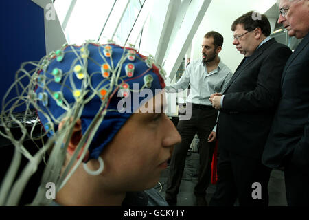 Taoiseach Brian Cowen mit Minister Batt O'Keefe (rechts) werden neurowissenschaftliche Experimente gezeigt, bei denen der Praktikant Ivo Kaethner (links) am Trinity College in Dublin eine Schädelkappe trägt. Stockfoto