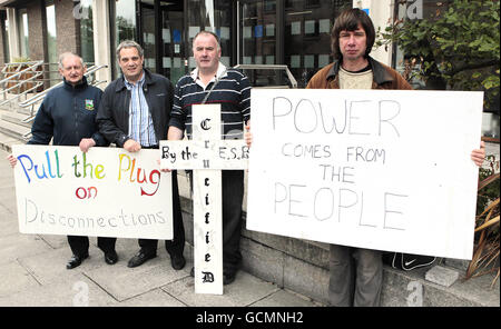 Seamus Sherlock aus Limerick (mit Kreuz), der sich an die Geländer des ESB-Hauptquartiers in Dublin gefesselt hat, wird von (von links) Ollie Ryan, Sinn Fein TD Aengus O'Snodaigh und Vincent Burke in einem Protest gegen Drohungen, ihn abzuschneiden, begleitet. Stockfoto