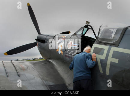 Nach der Landung auf dem Biggin Hill Airport in Kent blickt ein Mann in das Cockpit einer Mk VB Spitfire, nachdem er im August 1940 anlässlich des 70-jährigen Jubiläums von Winston Churchills Hommage an „die wenigen“ über den Flughafen geschutscht wurde. Stockfoto