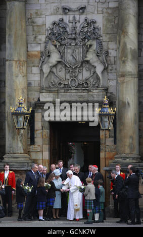 Die britische Königin Elisabeth II. Begleitet Papst Benedikt XVI., als er Blumen von Kindern empfängt, während er den Palace of Holyroodhouse in Edinburgh verlässt. Stockfoto