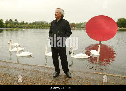 Der Künstler Anish Kapoor ist mit 'Sky Mirror Red 2007' im Rahmen seiner neuen Ausstellung 'Turning the World Upside Down' zu sehen, die bis zum 13. März 2011 vier reflektierende Edelstahlskulpturen in Kensington Gardens im Zentrum Londons umfasst. Stockfoto