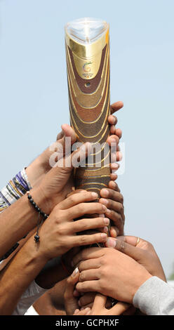 Sport - Commonwealth Games 2010 - Preview Day Seven - Delhi. Die Einheimischen legen ihre Hände um das Queens Baton am Eingang zum Athletes Village in Neu Delhi, Indien. Stockfoto