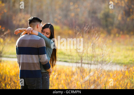 Ein junges asiatisches Paar genießt Eine romantische Zeit zusammen im Freien in Einem Park im Herbst und umarmt sich in der Wärme des... Stockfoto