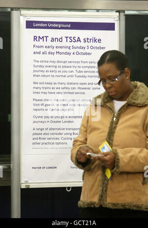 Eine Frau wird vor einem Plakat gesehen, auf dem die Passagiere der Londoner U-Bahn über Streikmaßnahmen am Bahnhof Elephant & Castle im Süden Londons informiert werden. Stockfoto