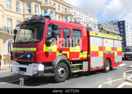 EIN OSTSUSSEX FEUER & RESCUE SERVICE VOLVO FEUER LKW VORBEI ENTLANG EINER HAUPTSTRAßE MIT BLAU LEUCHTET, BLINKT Stockfoto