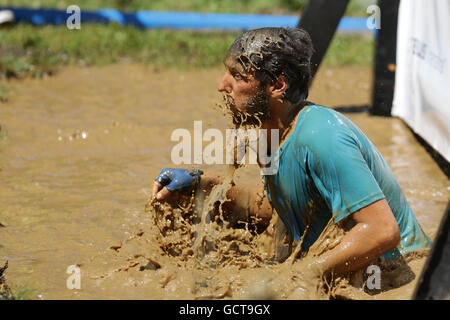 Sofia, Bulgarien - 9. Juli 2016: Ein Teilnehmer in schlammigem Wasser bei der Legion laufen Extremsport-Challenge in der Nähe von Sofia springt. Stockfoto