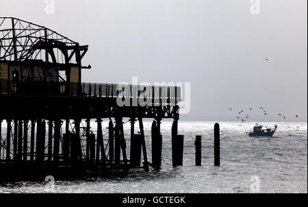 Ein Fischerboot passiert die Überreste des Piers in Hastings, East Sussex, nachdem es Anfang dieser Woche durch einen Brand zerstört wurde. Stockfoto