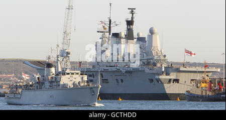 Die Minenjägerin HMS Hurworth (links) passiert das Flaggschiff der Royal Navy, HMS Ark Royal, neben der Hafenanlage in Portsmouth, nachdem Regierungsquellen angegeben haben, dass der Flugzeugträger und seine Flotte von Harrier-Jets im Rahmen der Strategic Defence and Security Review "mit sofortiger Wirkung" verschrottet werden sollen. Stockfoto