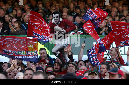 Llanelli Scarlets Fans zeigen ihre Unterstützung in den Tribünen als Sie zeigen einen Karton-Ausschnitt aus ehemaligen Llanelli und Wales Fliegen Sie halb Phil Bennett Stockfoto