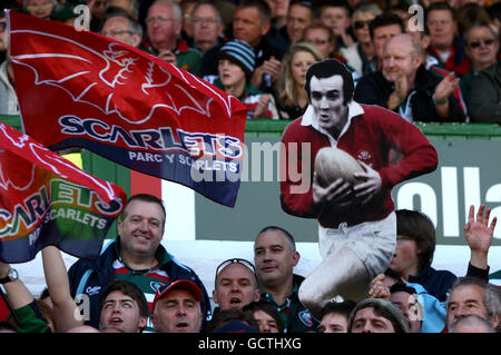 Llanelli Scarlets Fans zeigen ihre Unterstützung in den Tribünen als Sie zeigen einen Karton-Ausschnitt aus ehemaligen Llanelli und Wales Fliegen Sie halb Phil Bennett Stockfoto