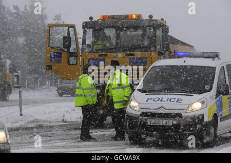 Polizeibeamte leiten einen Gitterwagen, da eine Straße über den North Yorkshire Moors heute nach Schneefällen und Schneestürmen gesperrt wurde. Stockfoto