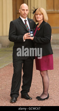 Steve und Angela Robinson, die Eltern von Rifleman Ross Robinson, mit seiner Queen's Gallantry Medal, die von Queen Elizabeth II. Posthum im Buckingham Palace in London verliehen wurde. Stockfoto