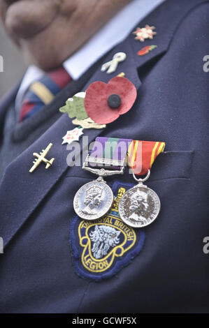 Ein Veteran der Royal British Legion trägt seinen Mohn, seine Medaillen und andere Abzeichen während einer kombinierten Heimkehr- und Gedenkparade entlang der Wootton Bassett High Street in Wiltshire. Stockfoto
