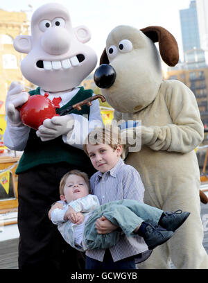 Die siebenjährige Lance und die dreijährige Miles Balynas treffen Wallace und Gromit am St Katherine Dock in London, wo sie Tee trinken, um den Beginn einer Spendenwoche für kranke Kinder zu markieren. Stockfoto