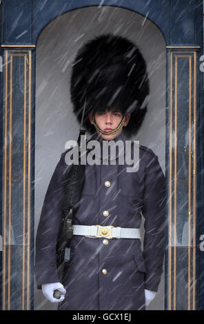 Ein Guardsman vor dem Buckingham Palace in London, als in der Hauptstadt Schnee zu fallen begann. Stockfoto