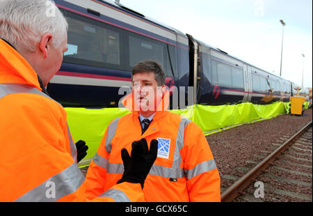 Der neue schottische Verkehrsminister Keith Brown mit Steve Montgomery (links), Managing Director von ScotRail, bevor er „Kill Frost“ verwendet, ein Enteisungsspray, das das Entfernen von Eis aus dem Fahrgestell eines Zuges während eines Besuchs im Eastfield-Depot von ScotRail in Glasgow verhindert und erleichtert. Stockfoto