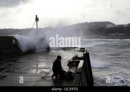 Das Ende des Piers war heute ein stürmischer Ort, wie dieser Fischer im Hafen von Scarborough herausfindet, als Stürme und hohe Gezeiten Wellen über die Meeresmauer schicken. Stockfoto