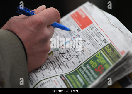 Ein Horse Racing Fan schaut auf die Rennkarte in der Racing Post auf der Kempton Park Racecourse, Middlesex. Stockfoto