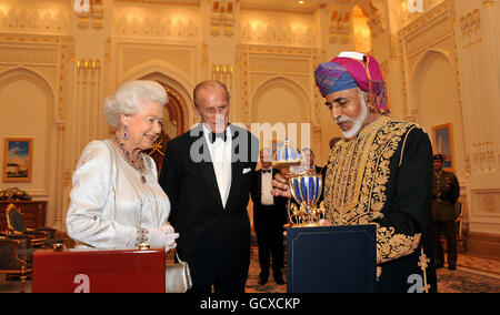 Königin Elizabeth II. Und der Herzog von Edinburgh freuen sich, als der Sultan von Oman ihnen vor einem Staatsbankett in seinem Palast in Muscat, Oman, ein goldenes musikalisches Ei im Faberge-Stil überreicht. Stockfoto