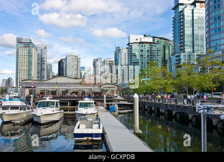 Apartmentgebäude, Yachthafen und Restaurant Carderos in Coal Harbour, Vancouver, einem Viertel am Wasser. Menschen, die entlang der Ufermauer spazieren. Stockfoto