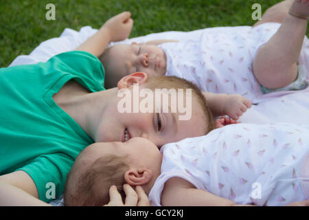 glücklich Bruder küssen eines seiner Zwillingsschwestern im park Stockfoto