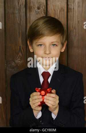 Junge in einem Anzug mit einem roten Sparschwein - Business-Konzept Stockfoto