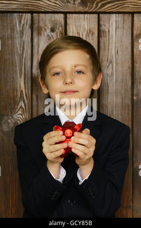 Junge in einem Anzug mit einem roten Sparschwein - Business-Konzept Stockfoto